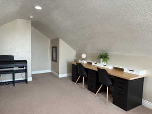 Office space featuring vaulted ceiling, baseboards, a textured ceiling, and carpet floors