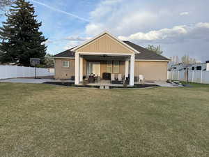 Back of property with a yard, ceiling fan, fence private yard, an outdoor living space with a fire pit, and a patio