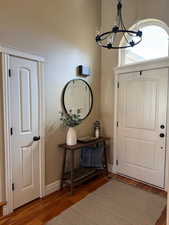 Foyer entrance featuring baseboards, a notable chandelier, and wood finished floors