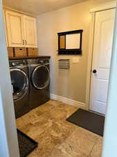 Laundry area featuring cabinet space, independent washer and dryer, a textured ceiling, and baseboards