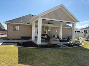 Rear view of house with a lawn, a patio, stucco siding, roof with shingles, and ceiling fan