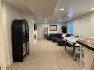 Living room with light colored carpet, baseboards, and recessed lighting