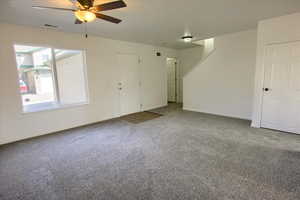 Unfurnished living room with visible vents, carpet flooring, baseboards, and ceiling fan