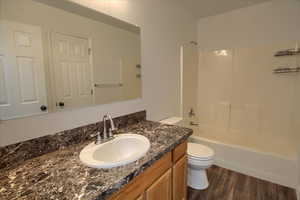 Full bathroom with shower / bath combination, wood finished floors, toilet, and vanity