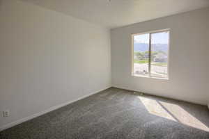 Carpeted empty room with visible vents and baseboards