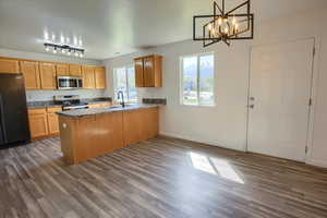 Kitchen with a peninsula, appliances with stainless steel finishes, dark wood-style floors, and a sink