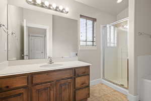Bathroom featuring tile patterned floors, baseboards, vanity, and a stall shower