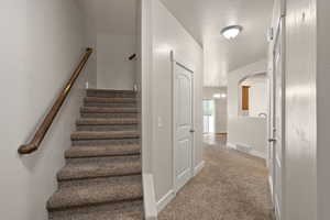 Staircase with arched walkways, baseboards, a notable chandelier, carpet flooring, and visible vents