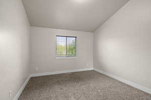 Carpeted empty room with vaulted ceiling and baseboards