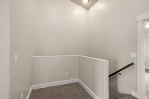 Hallway featuring baseboards, carpet flooring, and an upstairs landing
