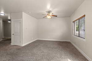 Spare room featuring carpet floors, a ceiling fan, and baseboards
