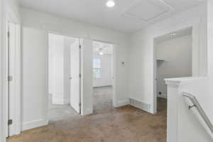 Hall with visible vents, carpet flooring, and baseboards