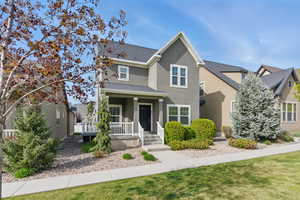 Traditional home with a shingled roof, covered porch, and stucco siding