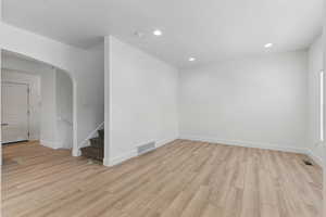 Interior space with arched walkways, visible vents, and light wood-type flooring