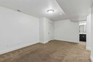 Unfurnished bedroom with visible vents, baseboards, carpet, and a textured ceiling