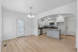 Kitchen with visible vents, a sink, arched walkways, light wood-style floors, and appliances with stainless steel finishes