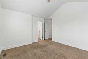 Carpeted spare room featuring lofted ceiling, a ceiling fan, visible vents, and baseboards