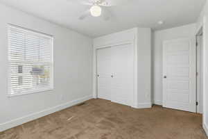 Unfurnished bedroom featuring carpet floors, multiple windows, visible vents, and a closet