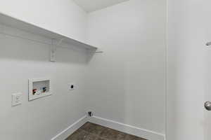 Clothes washing area featuring baseboards, washer hookup, electric dryer hookup, dark tile patterned flooring, and laundry area