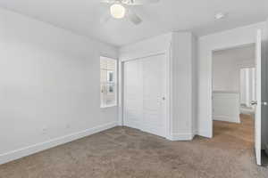 Unfurnished bedroom featuring a ceiling fan, baseboards, a closet, and carpet