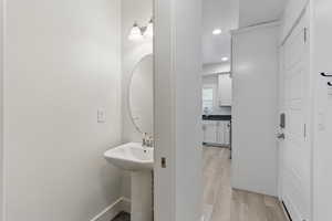 Bathroom with baseboards, wood finished floors, recessed lighting, and a sink