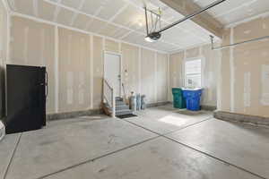 Garage featuring freestanding refrigerator and a garage door opener