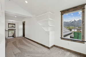 Carpeted empty room featuring baseboards, vaulted ceiling, a mountain view, and recessed lighting