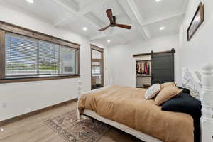 Bedroom featuring a barn door, recessed lighting, coffered ceiling, wood finished floors, and beamed ceiling