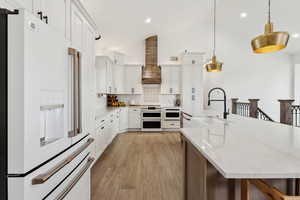 Kitchen with wall chimney exhaust hood, a sink, backsplash, white appliances, and pendant lighting