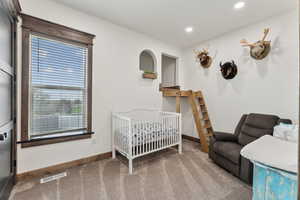 Carpeted bedroom featuring recessed lighting, visible vents, a crib, and baseboards