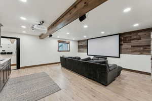 Home theater featuring recessed lighting, light wood-type flooring, wood walls, and baseboards