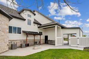 Back of house with a gate, a patio area, central air condition unit, stone siding, and fence