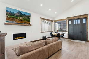 Living area with recessed lighting, a glass covered fireplace, vaulted ceiling, and wood finished floors