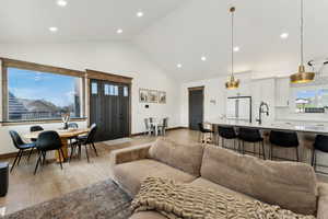 Living area with high vaulted ceiling, baseboards, light wood-style floors, and recessed lighting