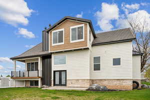 Back of property featuring a chimney, stone siding, and a yard