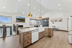 Kitchen with a sink, light wood-type flooring, a glass covered fireplace, white appliances, and light countertops