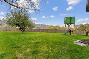 View of yard featuring a playground, fence, and a mountain view