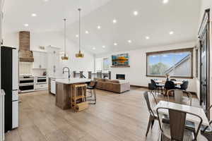 Kitchen featuring light countertops, a breakfast bar, a sink, double oven range, and custom range hood