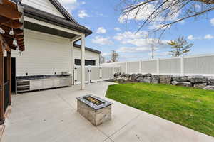 View of patio / terrace featuring a fire pit, an outdoor kitchen, a fenced backyard, and a gate