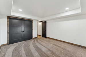 Unfurnished bedroom featuring recessed lighting, baseboards, carpet floors, and a raised ceiling