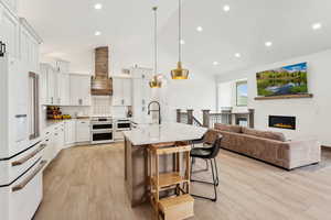 Kitchen featuring custom exhaust hood, tasteful backsplash, a sink, white appliances, and a kitchen bar