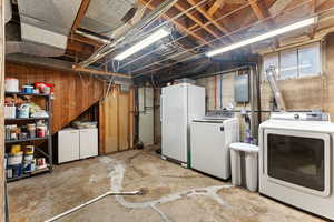 Basement with washing machine and clothes dryer, electric panel, and freestanding refrigerator