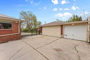 View of property exterior with an outdoor structure, brick siding, and fence