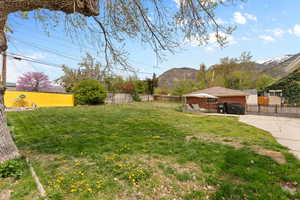 View of yard with a fenced backyard, concrete driveway, and a mountain view