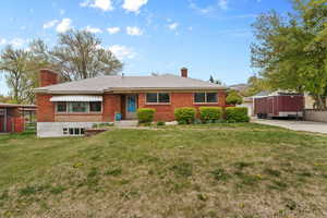 Ranch-style home with a front lawn, a chimney, and brick siding