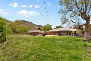 View of yard featuring fence, a mountain view, and a patio
