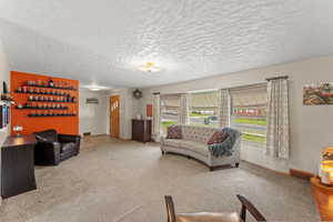 Carpeted living area with a textured ceiling, a bar, baseboards, and visible vents