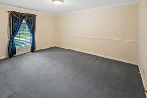 Unfurnished room with dark carpet, baseboards, crown molding, and visible vents