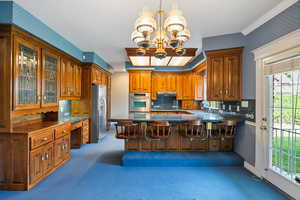 Kitchen featuring wallpapered walls, stainless steel appliances, an inviting chandelier, a sink, and carpet floors
