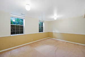 Carpeted spare room featuring visible vents and baseboards